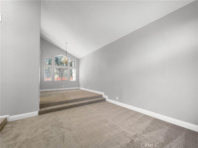 carpeted spare room featuring lofted ceiling and a notable chandelier