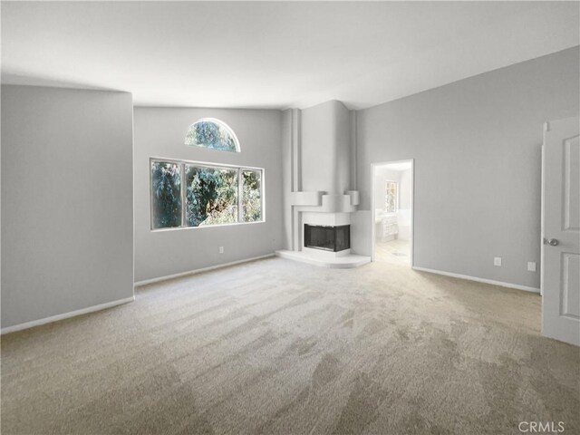 unfurnished living room featuring a multi sided fireplace and carpet