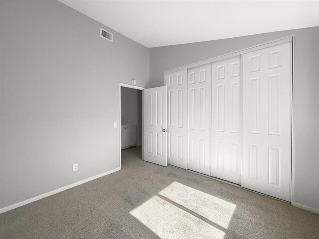 unfurnished bedroom with a closet, lofted ceiling, and light colored carpet