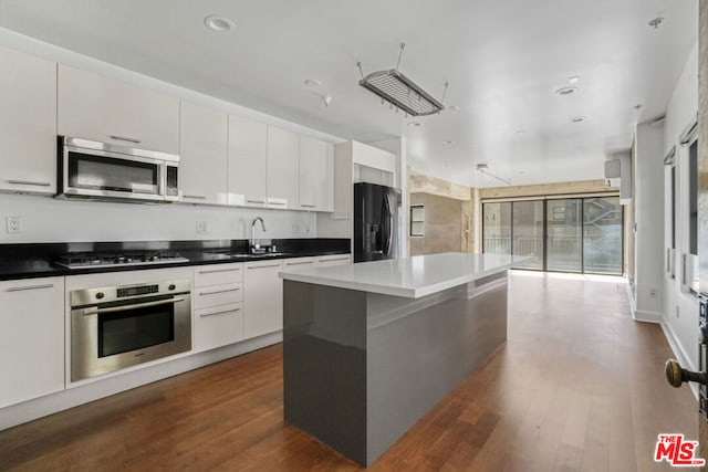 kitchen with white cabinets, a kitchen island, dark hardwood / wood-style flooring, stainless steel appliances, and sink