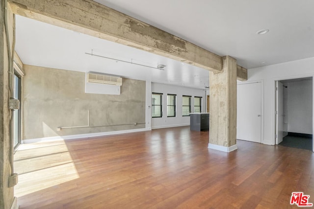 unfurnished living room featuring wood-type flooring and a wall mounted AC