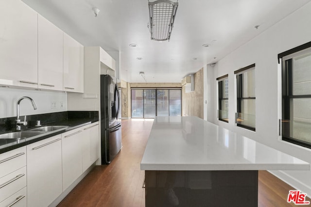 kitchen featuring stainless steel refrigerator with ice dispenser, white cabinetry, and sink