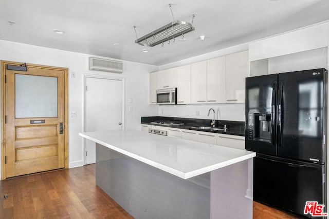 kitchen with stainless steel appliances, white cabinetry, a center island, and dark wood-type flooring