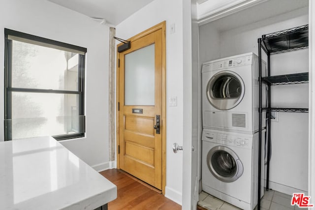 clothes washing area featuring wood-type flooring and stacked washer / dryer