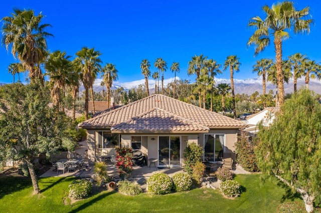 rear view of house with a mountain view, a lawn, and a patio area