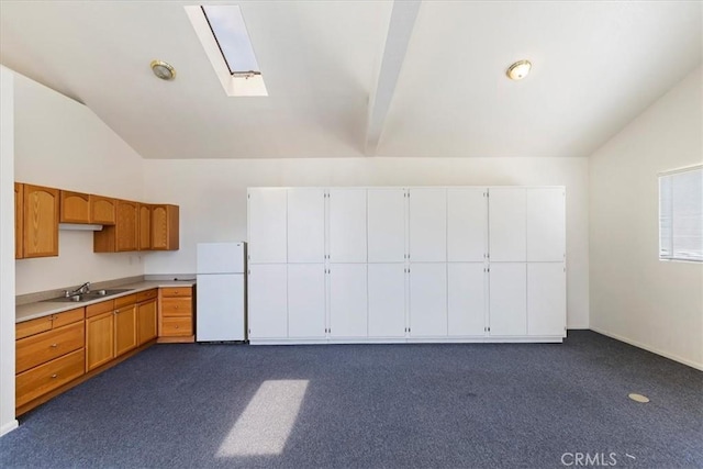 kitchen featuring lofted ceiling with skylight, sink, and white refrigerator