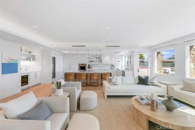 living room featuring wine cooler, indoor wet bar, and light wood-type flooring