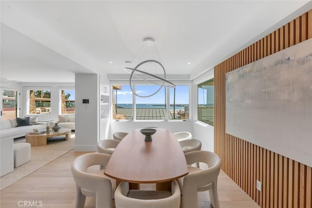 dining area with a water view, a chandelier, and light hardwood / wood-style floors