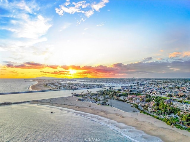 aerial view at dusk featuring a beach view and a water view