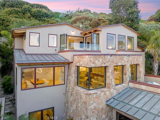 back house at dusk featuring a balcony