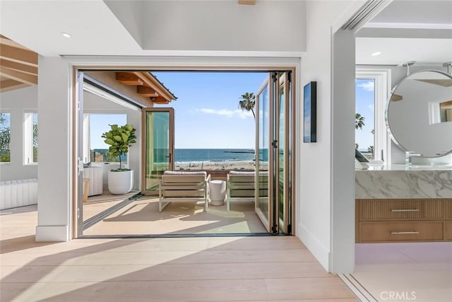 doorway with light hardwood / wood-style flooring, radiator heating unit, and a water view