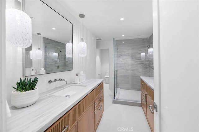 bathroom featuring vanity, a shower with door, and toilet