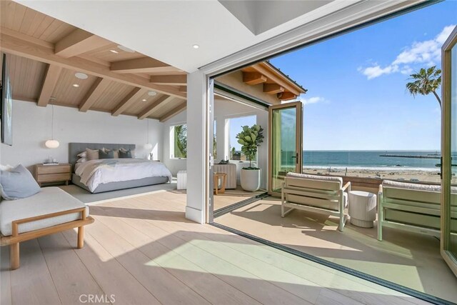 bedroom with wooden ceiling, lofted ceiling with beams, light hardwood / wood-style floors, a view of the beach, and a water view