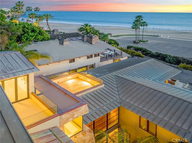 aerial view at dusk with a view of the beach and a water view