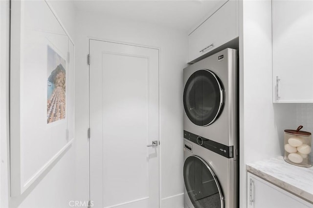 laundry area featuring stacked washer and dryer and cabinets