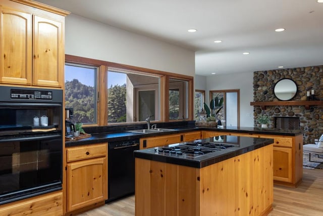 kitchen with a kitchen island, black appliances, sink, light hardwood / wood-style floors, and kitchen peninsula