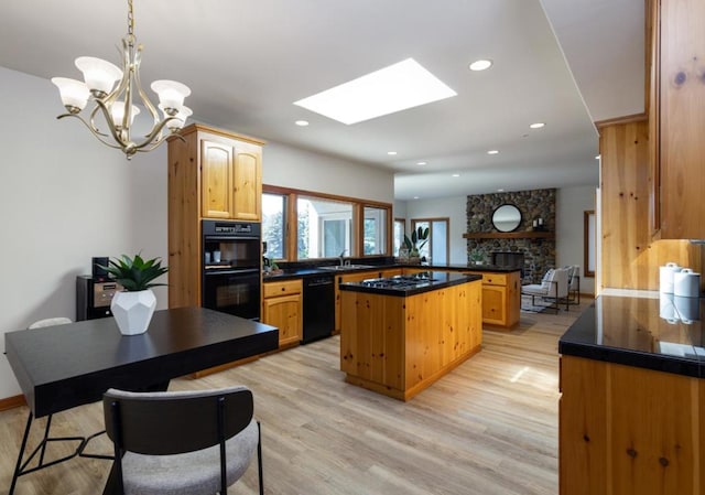 kitchen with a kitchen island, kitchen peninsula, decorative light fixtures, black appliances, and light hardwood / wood-style flooring