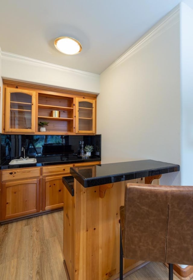 kitchen with sink, a breakfast bar area, kitchen peninsula, crown molding, and light wood-type flooring