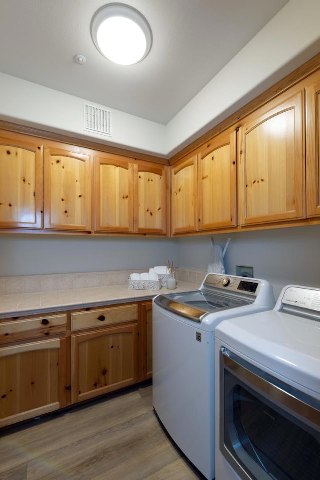 laundry room featuring separate washer and dryer, dark hardwood / wood-style flooring, and cabinets