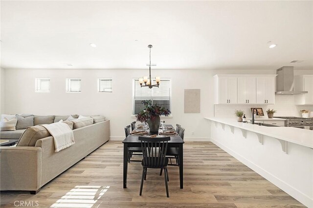 dining area featuring a notable chandelier, sink, and light hardwood / wood-style flooring