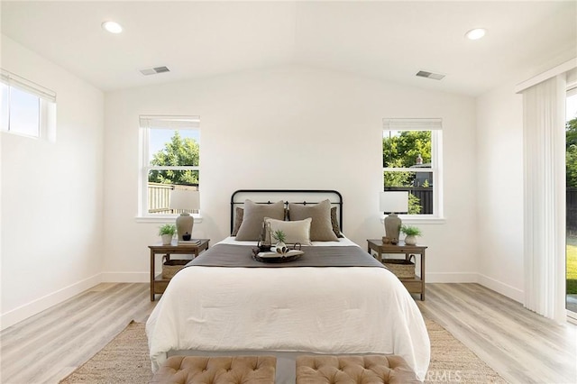 bedroom featuring lofted ceiling, multiple windows, and light wood-type flooring