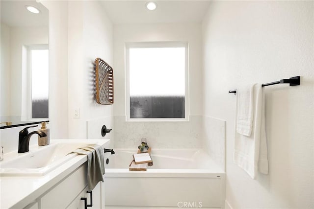 bathroom with vanity and a washtub