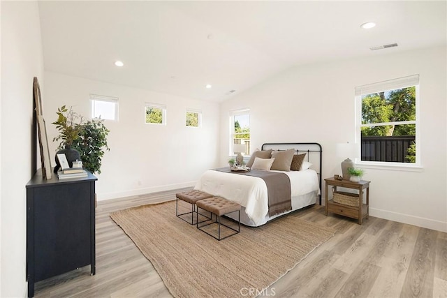 bedroom with light wood-type flooring, vaulted ceiling, and multiple windows