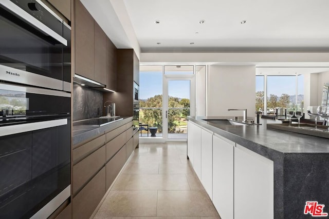 kitchen featuring dark brown cabinetry, sink, white cabinetry, black electric cooktop, and stainless steel double oven