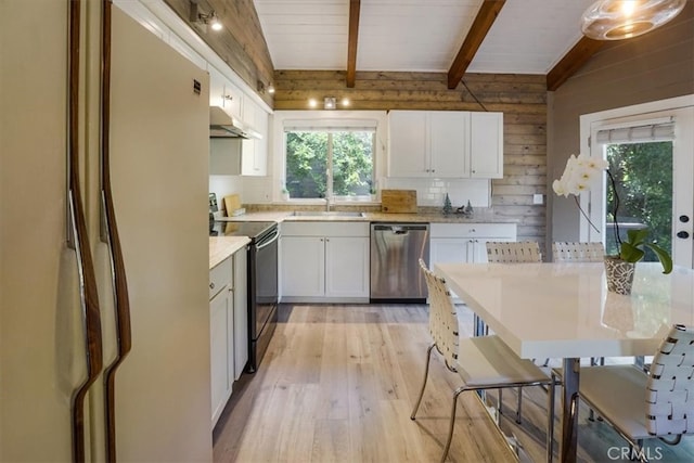 kitchen with light hardwood / wood-style floors, white cabinets, wooden walls, black electric range oven, and stainless steel dishwasher