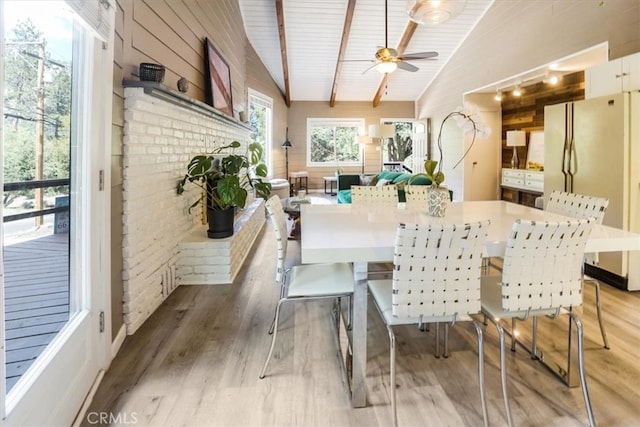 dining space featuring brick wall, a brick fireplace, lofted ceiling, ceiling fan, and hardwood / wood-style floors