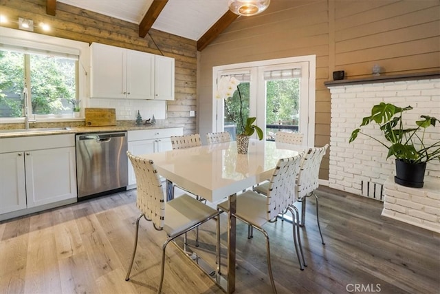 dining area with lofted ceiling with beams, light hardwood / wood-style flooring, a healthy amount of sunlight, and sink