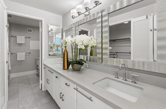 bathroom with toilet, vanity, and tile patterned flooring