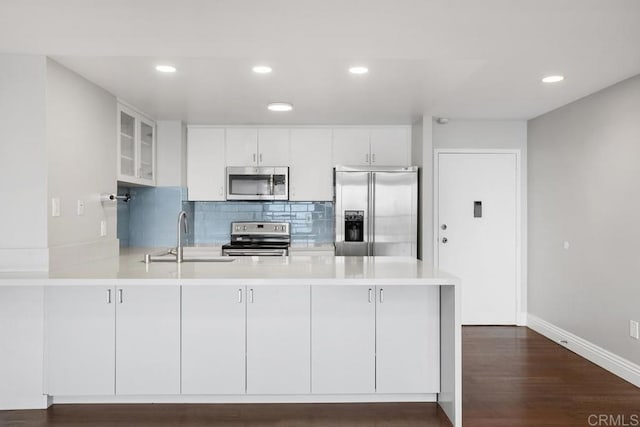 kitchen featuring sink, kitchen peninsula, white cabinets, and stainless steel appliances