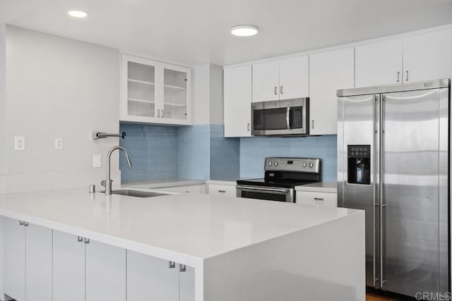 kitchen featuring white cabinets, stainless steel appliances, tasteful backsplash, sink, and kitchen peninsula