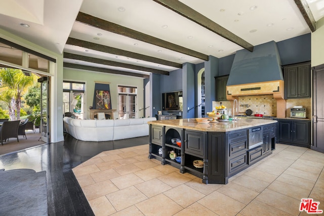 kitchen featuring beam ceiling, a kitchen island, decorative backsplash, light tile patterned floors, and custom range hood