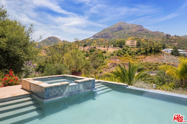 view of pool with an in ground hot tub and a mountain view