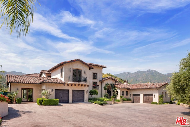 mediterranean / spanish-style home featuring a mountain view, french doors, a balcony, and a garage