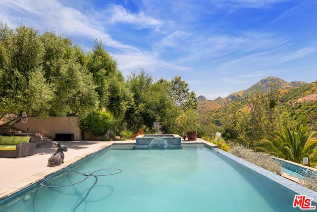 view of swimming pool featuring a mountain view, an in ground hot tub, and a patio