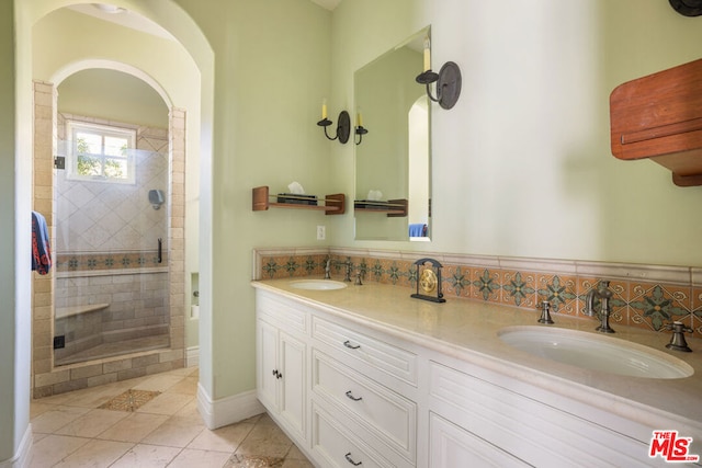 bathroom with tile patterned flooring, vanity, and a tile shower