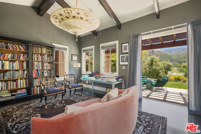 sitting room with beam ceiling, concrete floors, and a chandelier