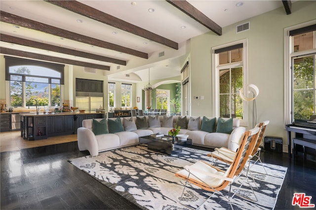 living room featuring beam ceiling, dark wood-type flooring, and a chandelier