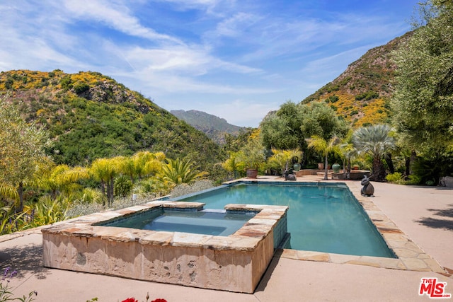 view of swimming pool with an in ground hot tub, a mountain view, and a patio area