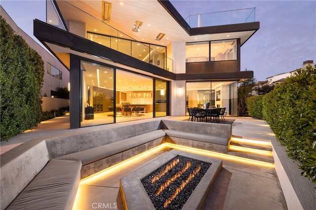 back house at dusk with an outdoor fire pit and a patio