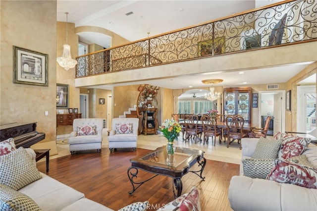 living room with a high ceiling, a chandelier, a wealth of natural light, and hardwood / wood-style floors