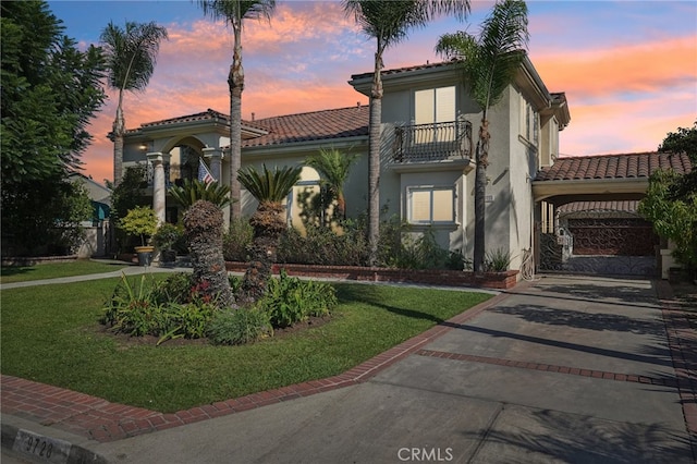 mediterranean / spanish-style house with a lawn and a balcony