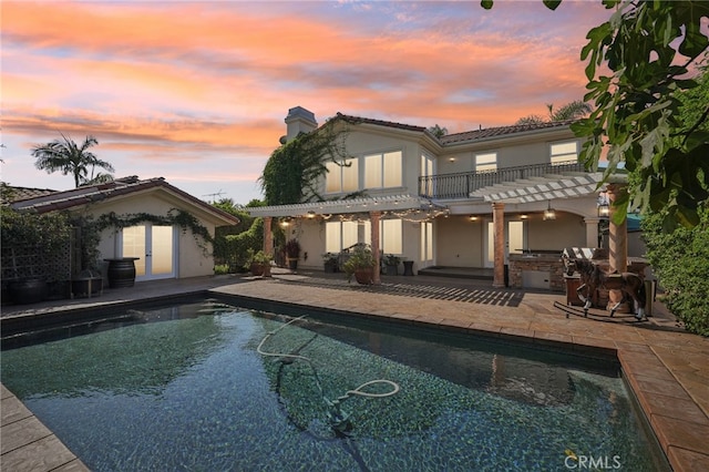 back house at dusk featuring a pergola and a patio area