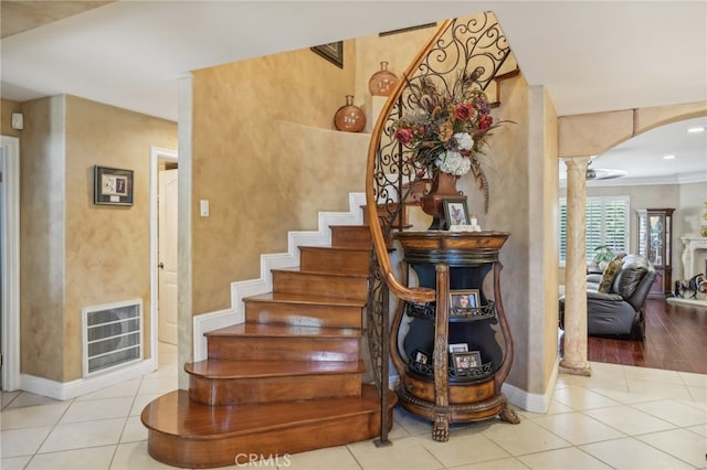 staircase featuring wood-type flooring, ornamental molding, and decorative columns