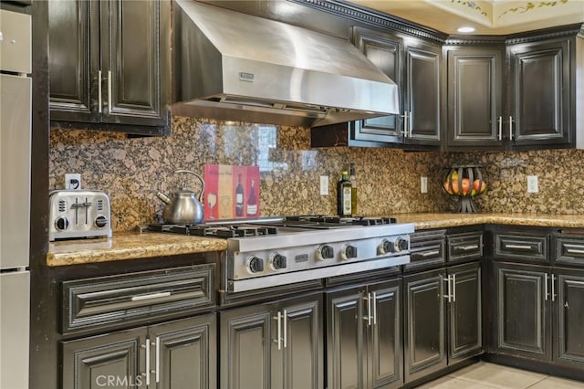 kitchen with wall chimney exhaust hood, white refrigerator, light tile patterned floors, and tasteful backsplash