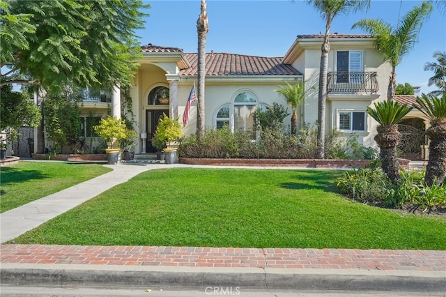 mediterranean / spanish-style house featuring a balcony and a front lawn