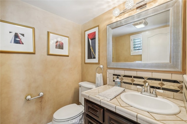 bathroom featuring tasteful backsplash, vanity, and toilet